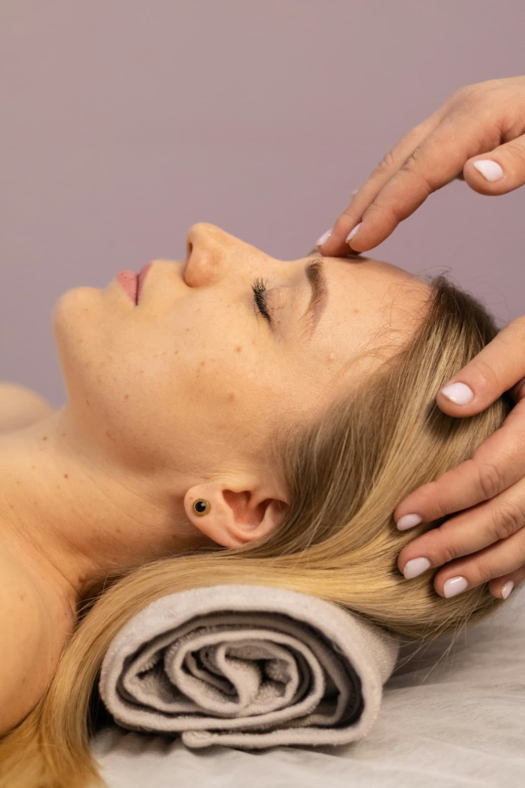 A woman receiving a gentle temple and scalp massage