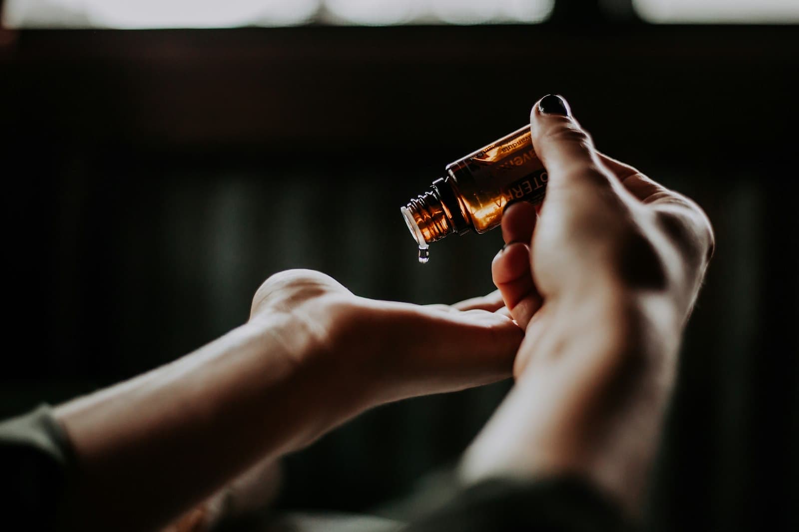 Oil being dropped from an amber bottle into an open palm