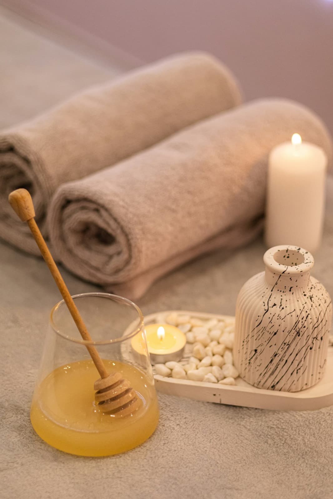 Candles, towels and a jar of honey arranged on a spa table