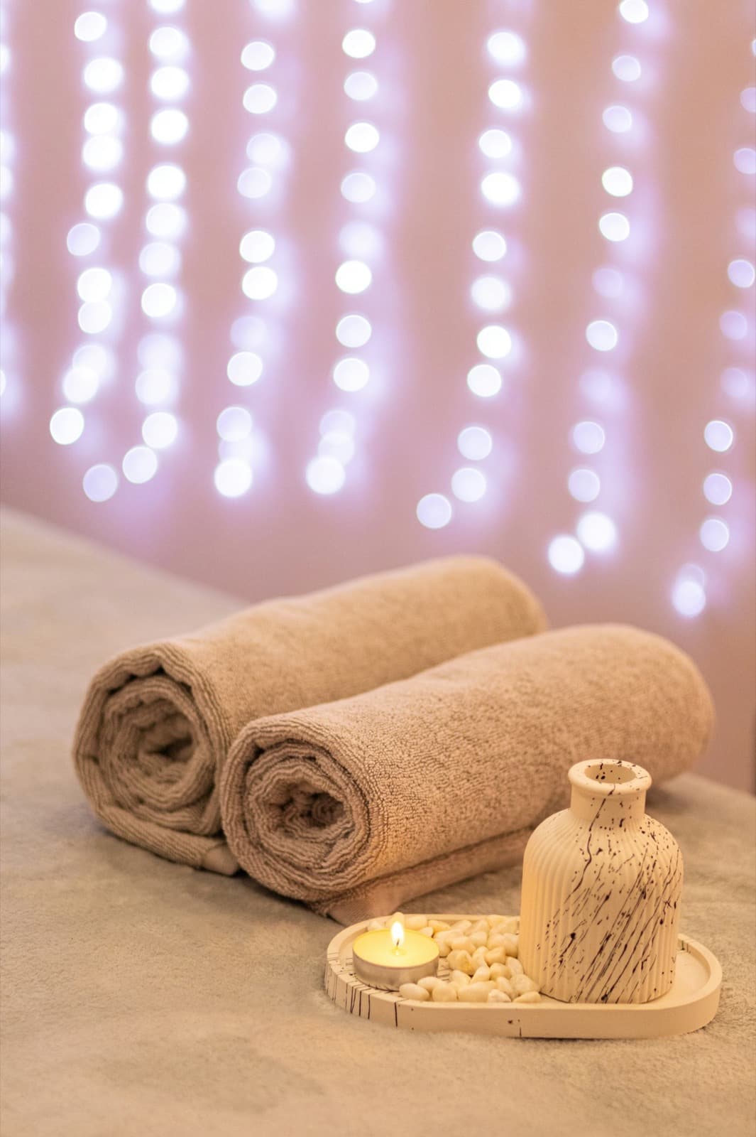 Rolled spa towels resting on a treatment bed