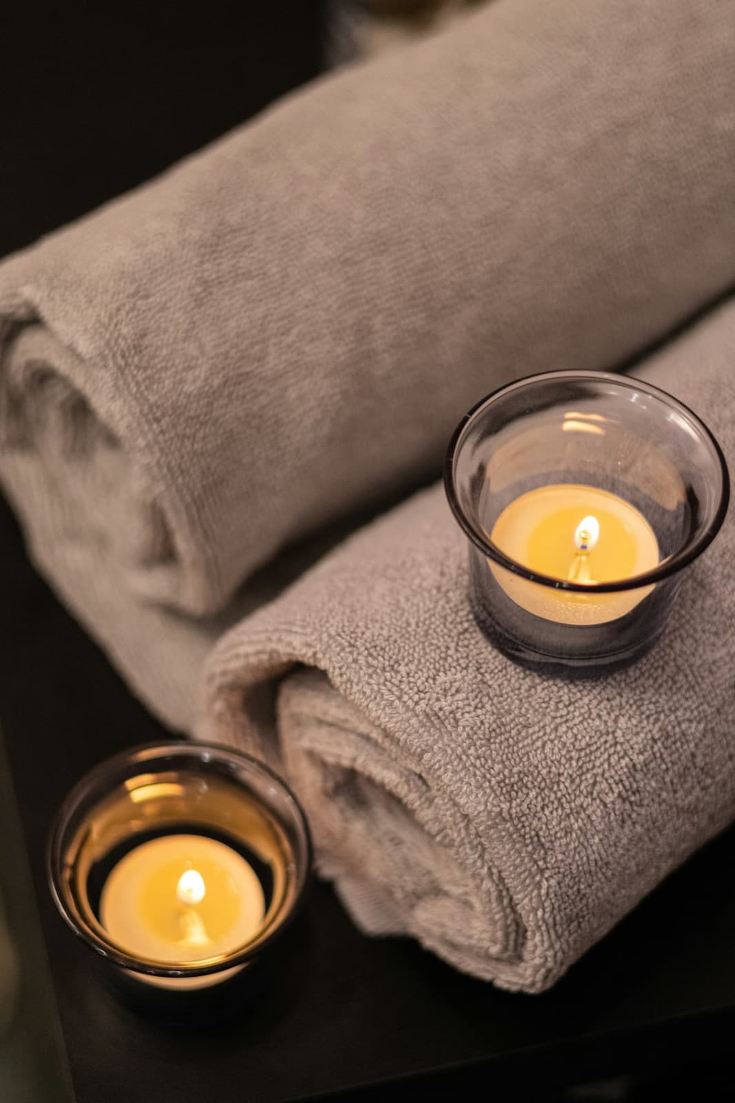 Lit candles arranged on a table in a dim, calming room