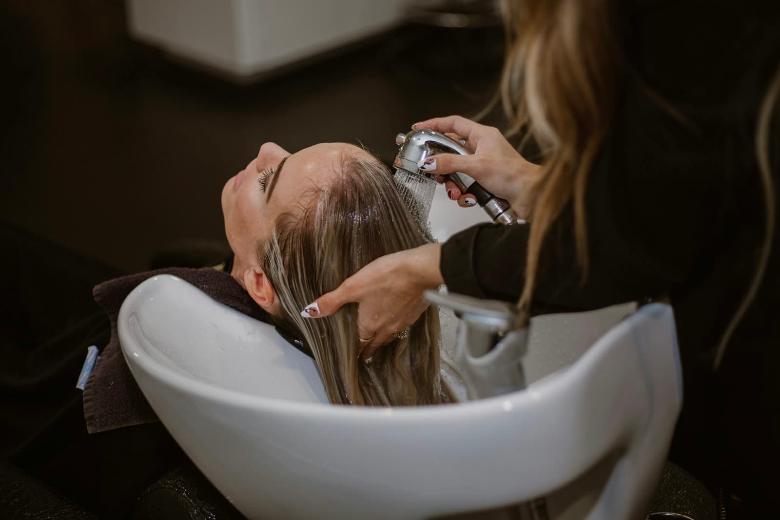 A stylist working on a client's hair in a salon chair