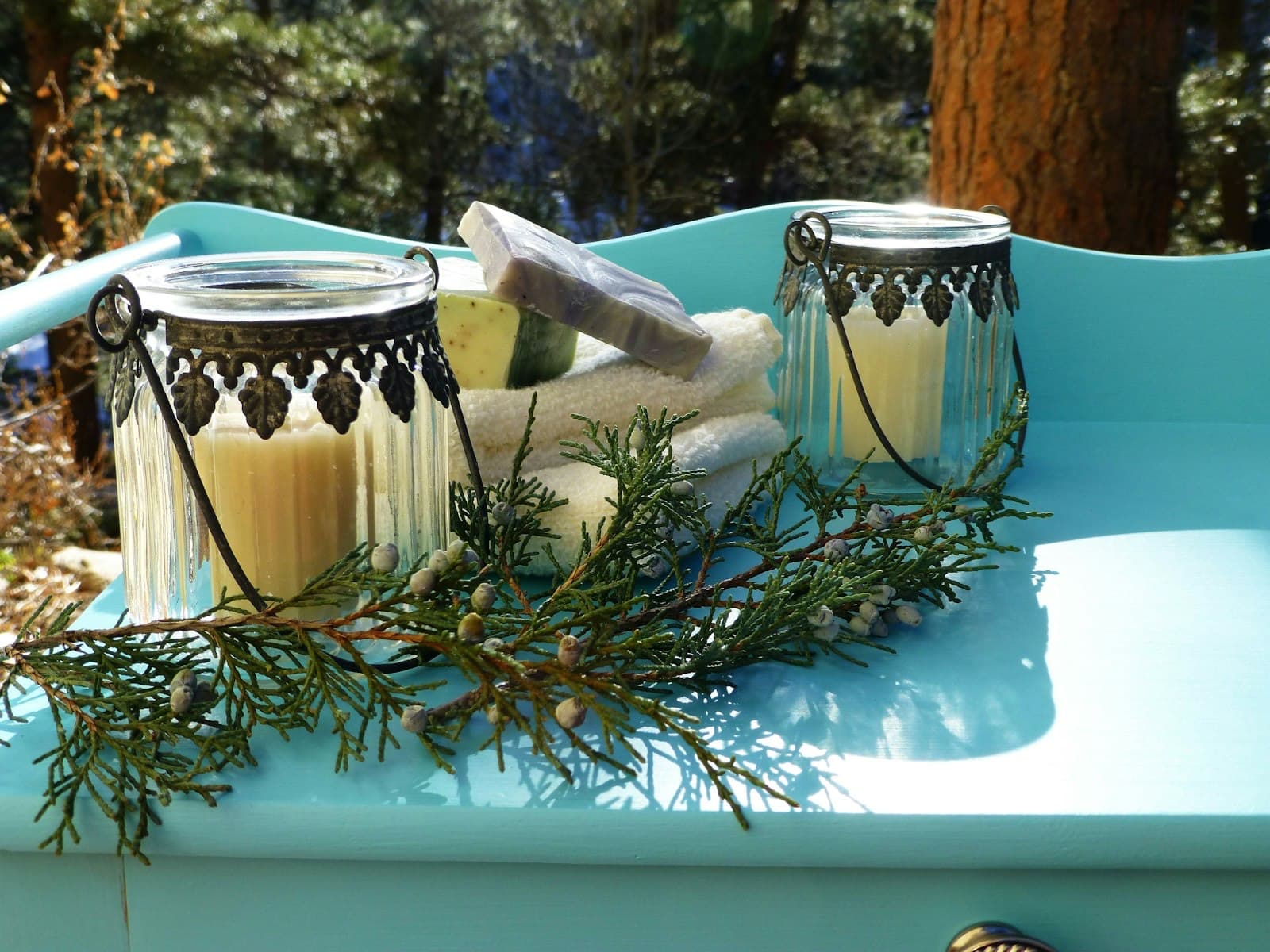 Two candles and folded towels on a blue spa table