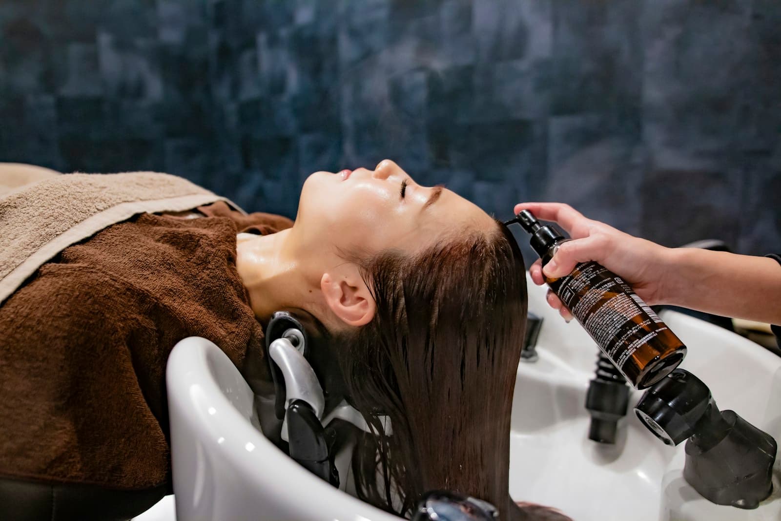 A woman having her hair washed at a spa basin